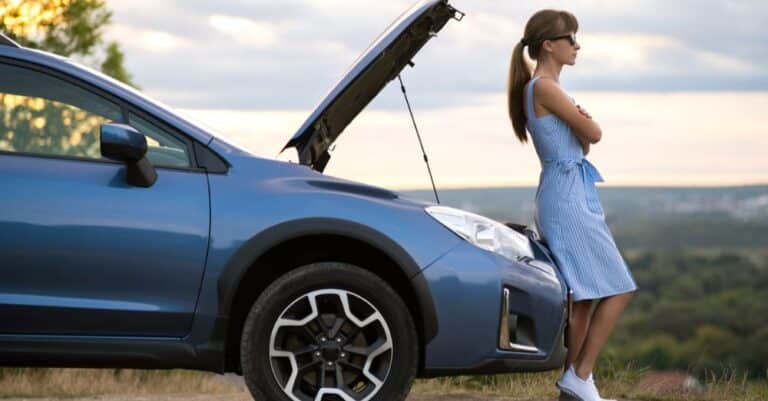 Woman with hood up on car waiting for repair